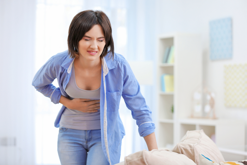 Woman holding her stomach in pain due to acute cutaneous nerve entrapment.